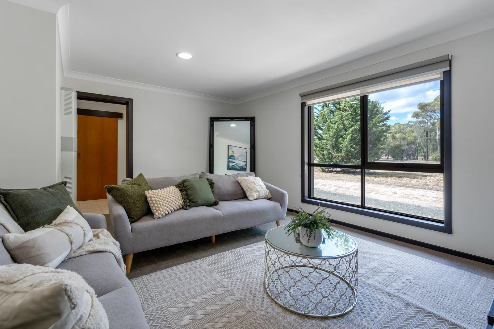 A light-filled living room with gum trees outside the window
